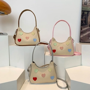 Tre borse a spalla in tela con toppe colorate a cuore su supporti geometrici da esposizione