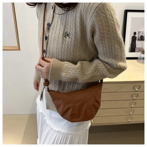 Close-up of caramel crescent moon shoulder bag featuring elegant vertical stitching