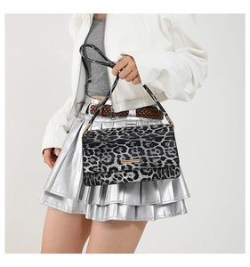 Detail of leopard print shoulder bag with gold metal buckle and textured animal pattern