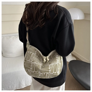 Detail of green and white striped knit hobo bag featuring zipper with knot puller