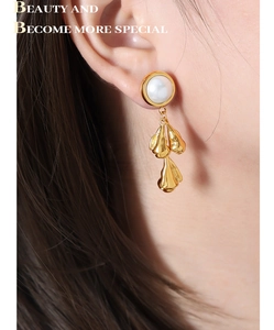 Macro detail of French retro shell pearl earrings with golden irregular metal droplets