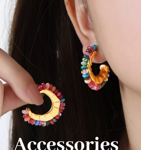 Detail view of gold C-shaped hoop earrings with colorful natural stone beads and crystals