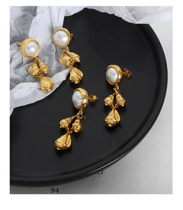 Detailed macro view of French style baroque pearl drop earrings with polished gold texture