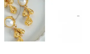 Detail of vintage gold-plated drop earrings with shell pearls on ceramic display