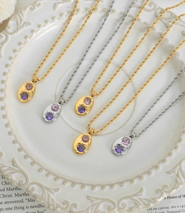 Détail de pendentifs ovales avec zircons étoilés sur chaînes torsadées dorées et argent