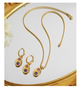 Détail d'un ensemble de bijoux dorés avec pendentifs ovales et pierres zircons violets