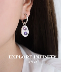 Détail de créoles en argent avec pendentif ovale gravé d'étoiles et zircone violette