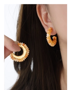 Close-up of gold C-shaped earrings with colorful natural stones for summer