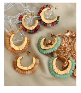 Detailed view of three pairs of C-shaped hoop earrings with colorful beads on satin background