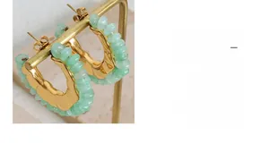 Detailed close-up of C-shaped gold-plated hoop earrings with light green natural stones
