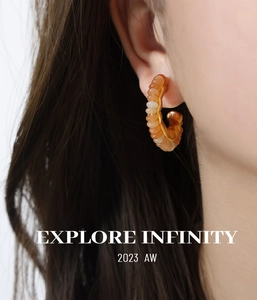 Close-up of model wearing C-shaped gold earrings with translucent orange beads