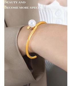 Détail d'un bracelet jonc minimaliste plaqué or avec perle d'eau douce au poignet féminin