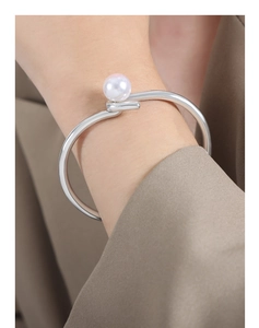 Détail d'un bracelet enveloppant plaqué or orné d'une perle d'eau douce lustrée