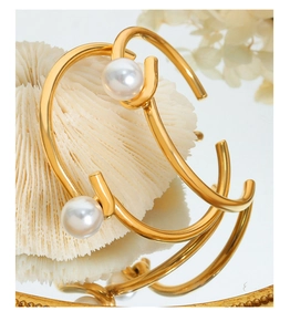 Détail de bracelets enveloppants dorés avec perles blanches sur pierre de corail