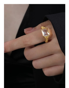 Makro-Detail eines rechteckigen Glassteins auf einem goldenen Titanring mit Seilmuster