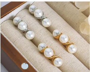 Detail of S-shaped gold and silver earrings with three white pearls on jewelry display