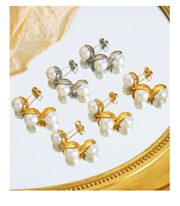 Detailed view of elegant gold and silver curved pearl earrings reflected on mirror