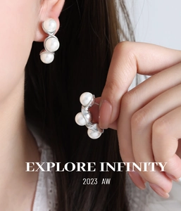 Close-up of elegant curved silver earrings with three white pearls on a model ear