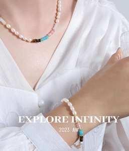 Détail du collier de perles d'eau douce et bracelet oeil de tigre sur chemisier blanc