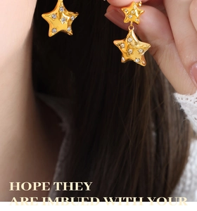 Macro shot of gold star stud earrings with white rhinestones worn on earlobe