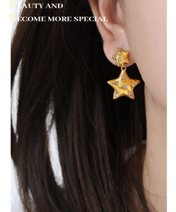 Macro shot of 18k gold star earrings with white cubic zirconia on a model's ear