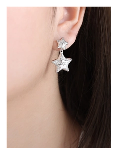 Macro detail of silver star drop earrings featuring crystal inlay on a female model