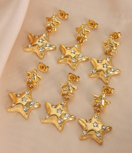 Close-up of gold-plated star earrings with inlaid sparkling crystals on silk fabric