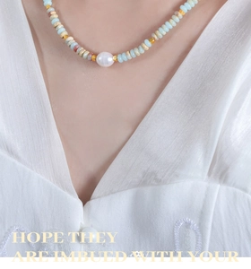 Detail of colorful beaded necklace featuring a white pearl and blue stones on a model