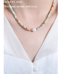Detail of bohemian necklace featuring colorful natural stones and a freshwater pearl accent