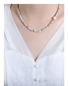Close-up of a beaded necklace with colorful natural stones and a white freshwater pearl