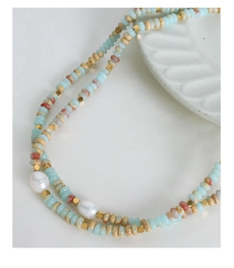 Detail of bohemian necklace featuring colorful natural stones and baroque pearls on titanium steel