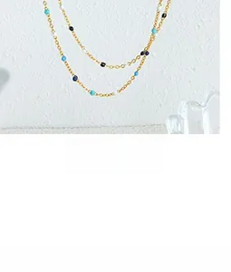 Dettaglio della collana a catena dorata con perline colorate azzurre, bianche e nere