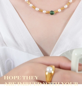 Dettaglio della collana di perle con perla verde e anello di perle coordinato indossato