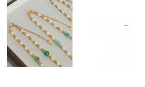 Dettaglio collana di perle d'acqua dolce con pietre verdi e perline dorate sul vassoio