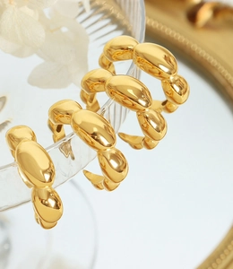 Detailed view of three polished gold C-shaped rings hanging on glass edge with warm lighting