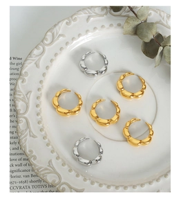 Set of six chunky 18k gold and silver punk rings displayed on a white vintage ceramic tray