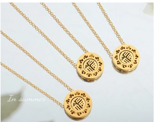 Detailed view of hollow gold-plated round Fu character pendants on minimalist chains