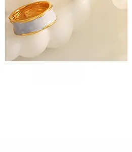 Macro shot of gold and white enamel wavy ring displayed on a cloud shaped ceramic tray