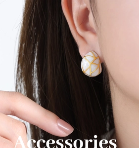 Vue détaillée de boucles d'oreilles en émail blanc avec motif géométrique doré sur mannequin