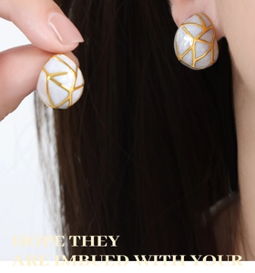 Détail macro de boucles d'oreilles goutte en émail avec motifs géométriques dorés