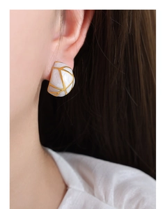 Détail de boucles d'oreilles en titane plaqué or avec texture marbrée portée