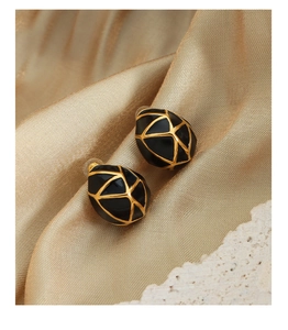 Détail de boucles d'oreilles en émail et bordure dorée sur un tissu élégant en soie champagne