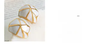 Vue détaillée de boucles d'oreilles vintage en émail avec motifs de grille dorés
