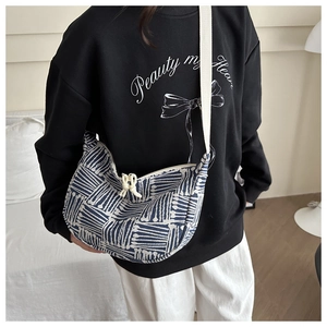 Close-up of crescent canvas crossbody bag with blue geometric pattern and knot zipper pull