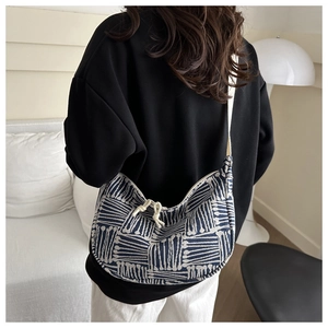 Detail of woven hobo bag with geometric stripes and adjustable cream textile strap