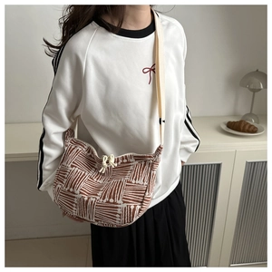 Model showing a geometric jacquard crescent tote with striped pattern and wide strap