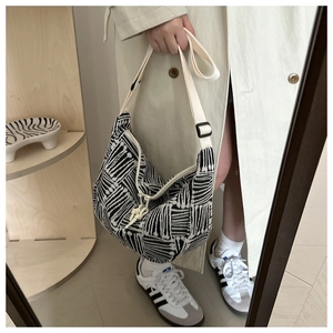 Detail of black and white striped canvas tote bag with adjustable beige shoulder strap