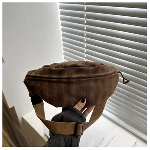 Close-up of brown corduroy waist bag showing fine ribbed texture and adjustable strap