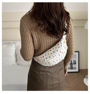 Detail of white floral crossbody waist bag worn by a model in a cozy home setting