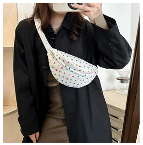 Close-up of white crossbody bag with colorful polka dots on a black coat model